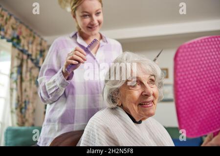 Weibliche Mobile Friseur Schneiden Senior Womans Haar zu Hause Stockfoto