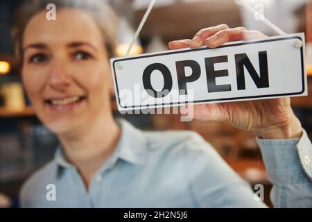 Inhaberin Eines Kleinen Unternehmens, Das Sich An Der Tür Ein Schild Öffnet Stockfoto