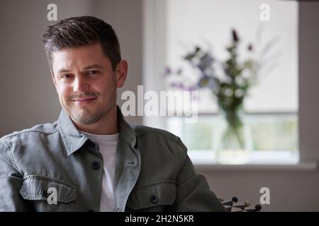 Porträt Von Nachdenklich Und Inhalt Mann, Der Zu Hause Auf Dem Stuhl Sitzt Stockfoto