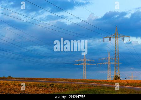 Strommasten, die gegen den blau bewölkten Himmel stehen Stockfoto