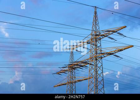 Strommasten, die gegen den blau bewölkten Himmel stehen Stockfoto