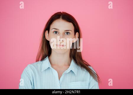 Lächelnde junge Frau, die über Lautsprecher auf dem Smartphone spricht, während sie zu Hause mit gekreuzten Beinen sitzt Stockfoto