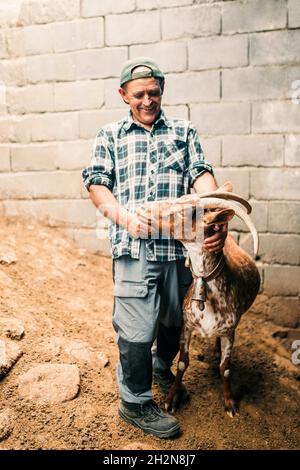 Männlicher Bauer liest Tagebuch, während er am Eimer steht Stockfoto