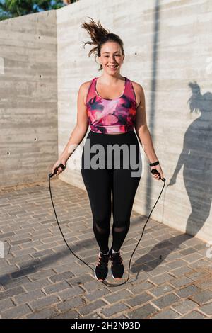 Die Sportlerin lächelt, während sie an sonnigen Tagen an der Wand hüpft Stockfoto