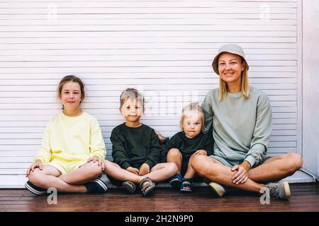 Lächelnde Mutter mit Söhnen und Tochter, die vor dem Fensterladen sitzen Stockfoto