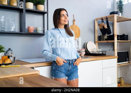 Schöne junge Frau, die ein Glas Wasser an der Küchentheke hält Stockfoto