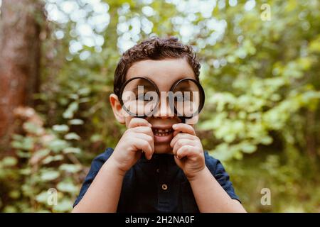 Verspielter Junge, der durch die Lupe schaut Stockfoto