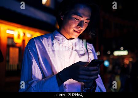 Schöner junger Mann, der nachts über das Mobiltelefon surft Stockfoto