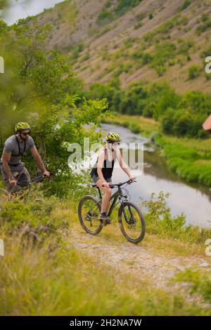Porträt eines Paares, das zusammen mit dem Fahrrad den Hügel hinunterfährt Stockfoto