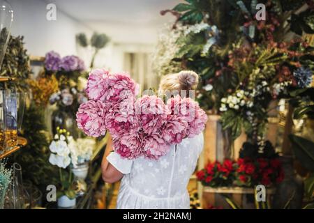 Reife weibliche Floristin, die Blumen in der Vase im Laden arrangiert Stockfoto