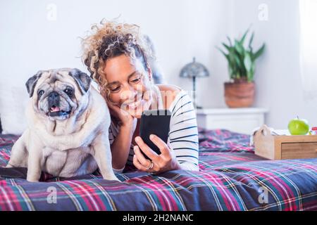 Lächelnde Frau, die im Schlafzimmer mit Hund auf dem Bett lag Stockfoto