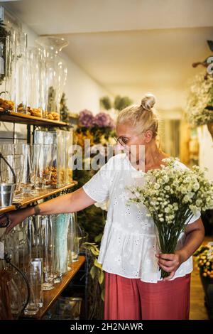 Weibliche Floristin trägt rosa Blumenstrauß während der Arbeit im Geschäft Stockfoto