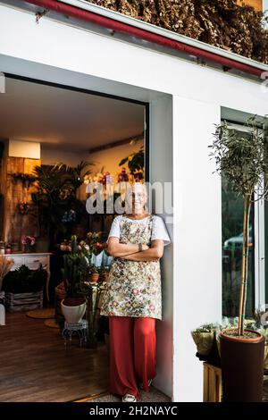 Blonde weibliche Floristin, die Blumen außerhalb des Ladens arrangiert Stockfoto