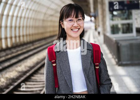 Lächelndes Teenager-Mädchen im Rucksack am Bahnhof Stockfoto