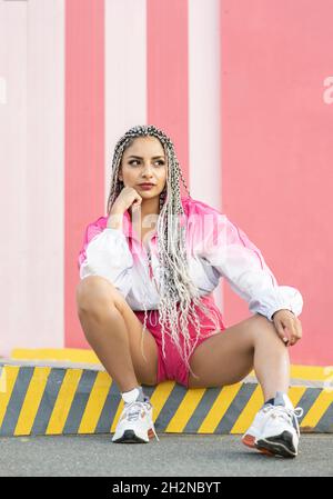 Junge Frau wirft Haare an rosa Wand Stockfoto
