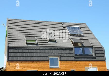 Modernes Hausdach mit Solar Water Heater, Sonnenkollektoren und Oberlichter. Schönes neues modernes Haus mit Sonnenkollektoren, Oberlichtern und Dormer. Modder Stockfoto