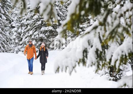 Mann und Frau halten sich beim Gehen auf Schnee die Hände Stockfoto