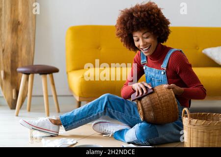 Rotschopf Afro Frau Polieren Korbkorb im Wohnzimmer Stockfoto