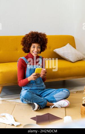 Afro Frau Polieren Korbkorb im Wohnzimmer Stockfoto