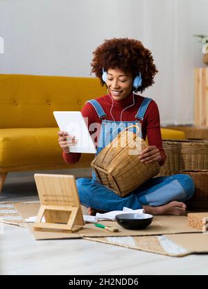 Frau mit Korbkorb mit digitalem Tablet im Wohnzimmer Stockfoto