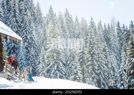 Mittelerwachsenes Paar, das an sonnigen Tagen im Winter auf einem Holzgeländer sitzt Stockfoto