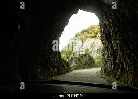 Blick vom Auto aus von einem felsigen Tunnel auf einer Bergstraße Stockfoto