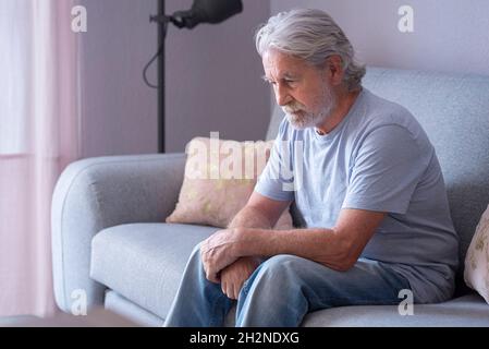 Einsamer älterer Mann, der zu Hause auf dem Sofa sitzt Stockfoto