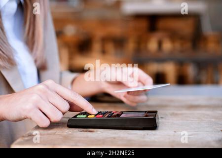 Junge Geschäftsfrau, die am Kaffeetisch mit Kreditkarte bezahlt Stockfoto