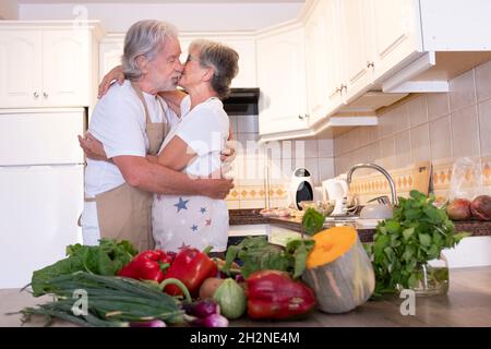Ältere Paare küssen sich, während sie in der Küche stehen Stockfoto