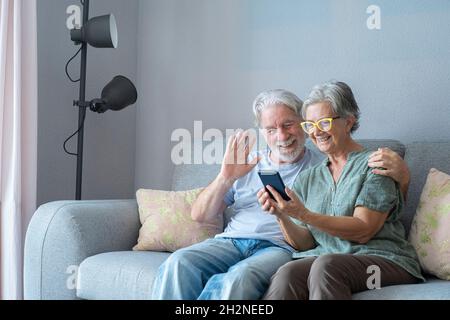 Lächelnder älterer Mann winkt während eines Videoanrufs von einer Frau zu Hause Stockfoto
