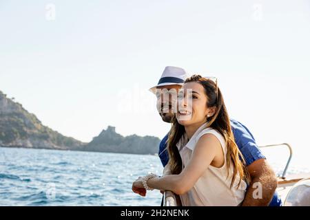 Glückliches Paar, das während eines sonnigen Tages im Motorboot zusammen steht Stockfoto
