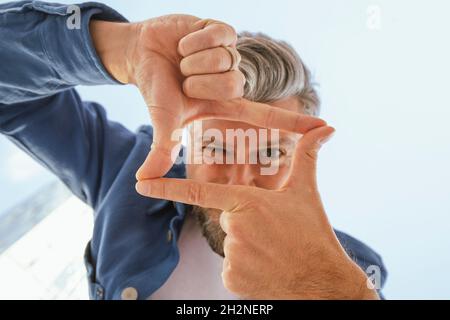 Fröhlicher bärtiger Mann, der Rahmen mit Finger macht Stockfoto
