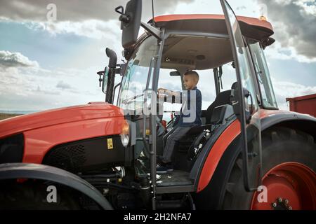 Junge fährt Traktor auf dem Feld Stockfoto