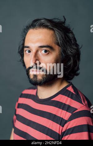 Selbstbewusster Mann mit schwarzen Haaren in gestreiftem T-Shirt Stockfoto