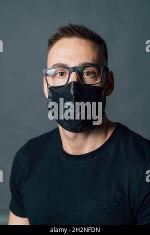 Mittelerwachsener Mann mit Brille und Gesichtsschutzmaske im Studio Stockfoto