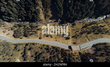 Luftaufnahme einer kurvenreichen Straße entlang des Bergflusses Stockfoto