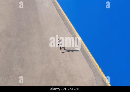 Engagierte Sportlerin, die an sonnigen Tagen an der blauen Wand unterwegs ist Stockfoto