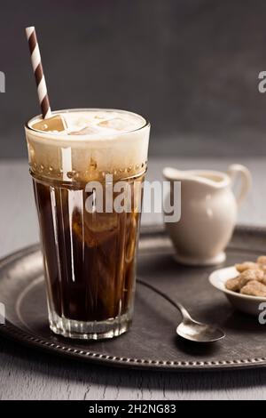Ein mehrlagiges Kaffeegetränk mit Eis, Espresso und Milch oder Creme, das in einem großen Glas mit Stroh und Löffel vermischt wird Stockfoto