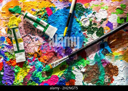 Malen Sie Tuben und Pinsel auf einer unordentlichen Palette Stockfoto