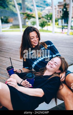 Junge Freundinnen genießen einen Drink, während sie auf der Treppe sitzen Stockfoto