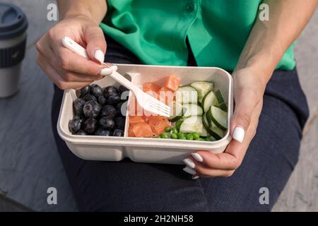 Frau, die Obst aus der Lunchbox isst Stockfoto