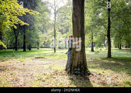 Frau umarmt Baum im park Stockfoto