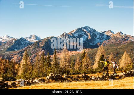 Zwei Wanderer, die im Herbst an einem kleinen Teich in den Ennstal Alpen vorbeiwandern Stockfoto