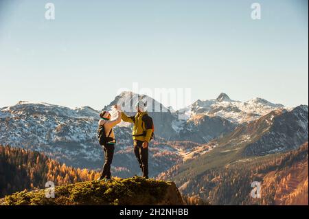 Zwei Wanderer balancieren in den Ennstal-Alpen spielerisch gemeinsam über einen Haufen Felsen Stockfoto