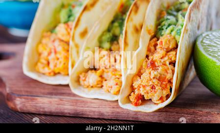 Mexikanische Tacos mit gebratenem gehacktem Huhn und Guacamole-Sauce auf Holzbrettern. Tacos, Guacamole und Kalk auf Holzgrund. Mexikanische Küche Stockfoto