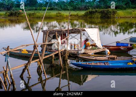 Mehrere kleine Boote wurden mit einem Mann zusammengebunden, der auf seinem Boot hockte. Stockfoto