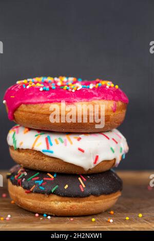 Schönes, süßes Essen. Stapel von glasierten bunten verschiedenen Donuts mit Spritzern auf einem grauen Hintergrund. Stockfoto