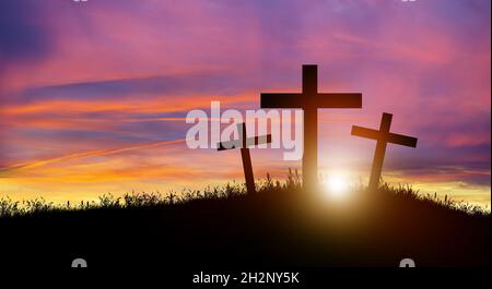 Drei christliche Kreuz auf dem Hügel bei Sonnenuntergang. Kreuzigung von Jesus Christus. Weihnachten, Ostern, Erlösung der Sünden, Opfer und Religion Konzept. Stockfoto