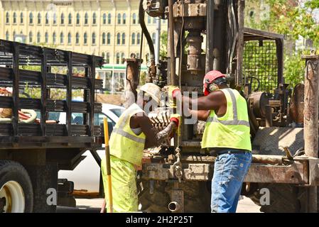 Zwei afroamerikanische Bauarbeiter bohren sicher ein Loch im Stadtzentrum, das an den Wisconsin River, Urban Renewal, Milwaukee, Wisconsin, USA, angrenzt. Stockfoto