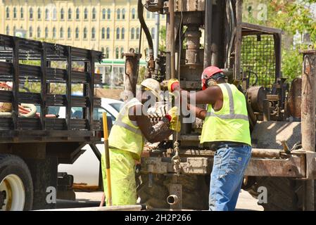 Zwei afroamerikanische Bauarbeiter bohren sicher ein Loch im Stadtzentrum, das an den Wisconsin River, Urban Renewal, Milwaukee, Wisconsin, USA, angrenzt. Stockfoto